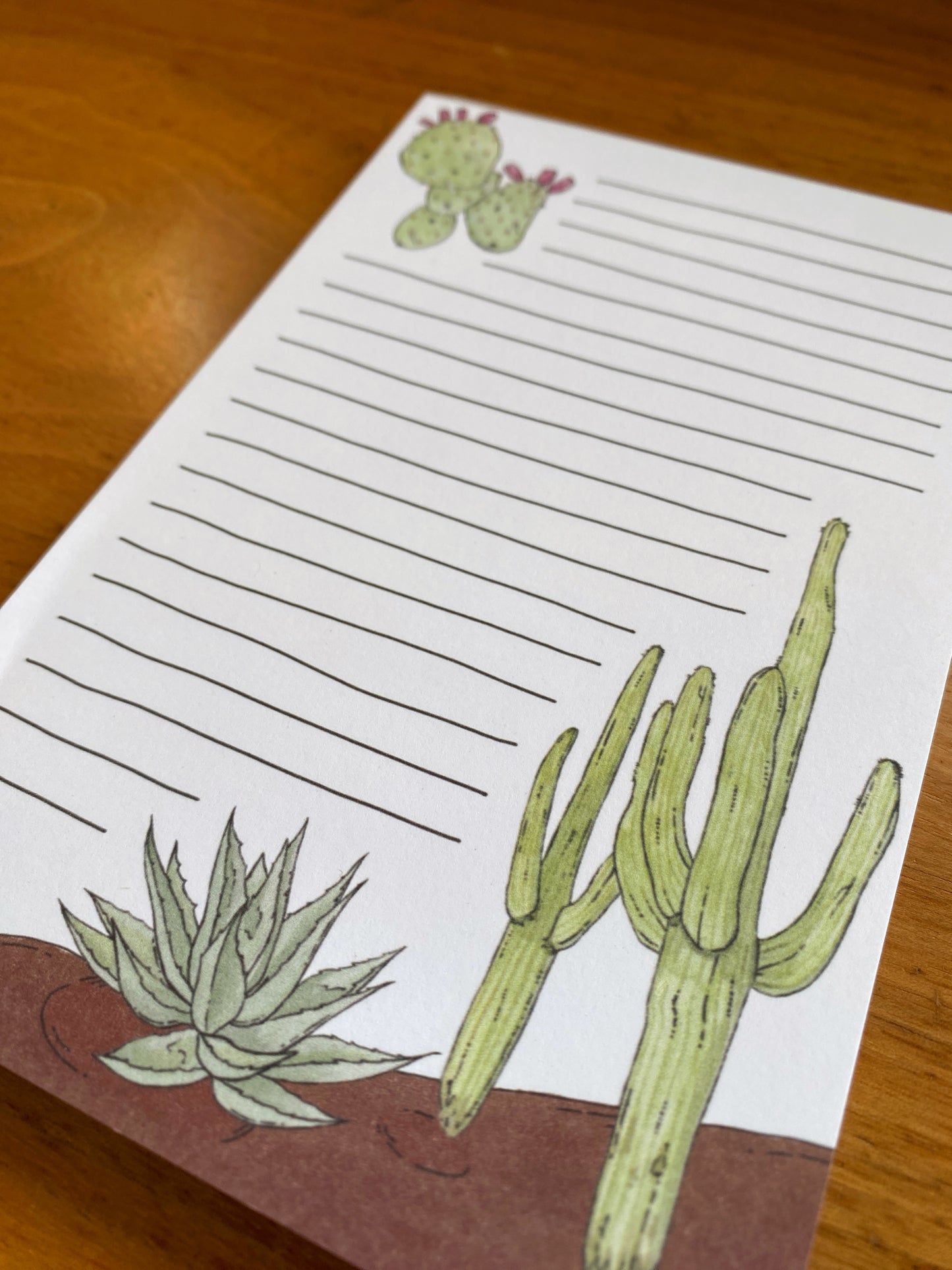 Lined notepad with cactus watercolor paintings.