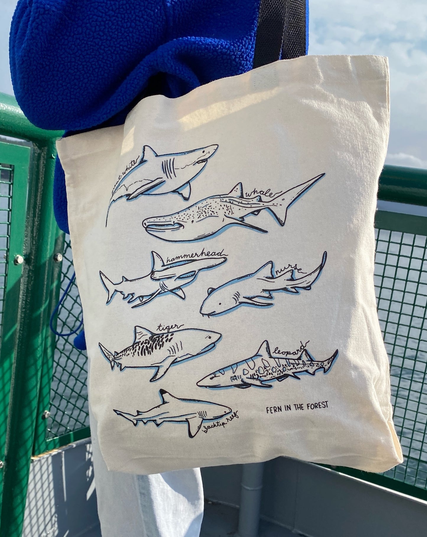 A cream canvas tote bag with printed shark illustrations.