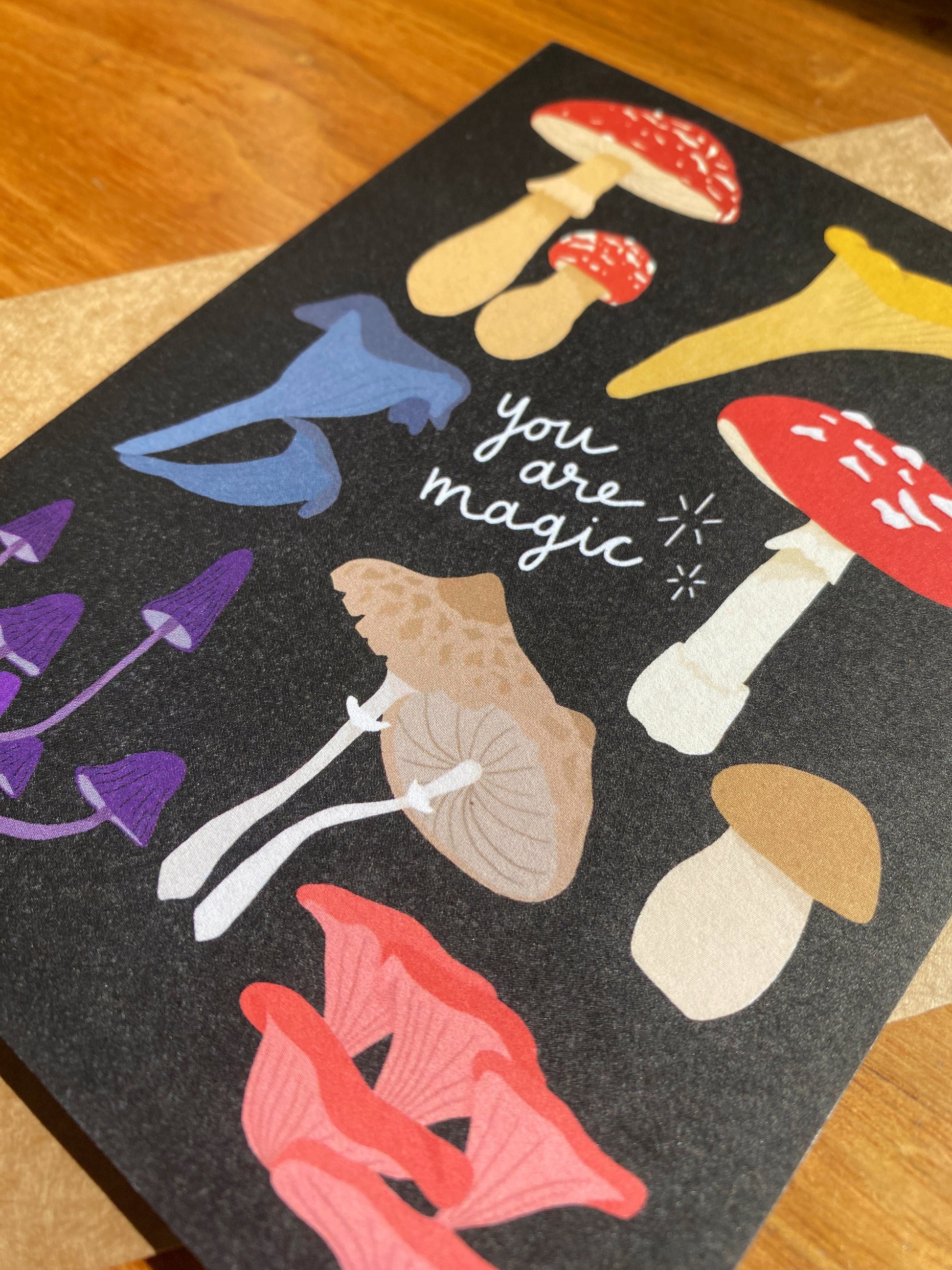 greeting card with black background, multiple mushrooms and says "You are magic"