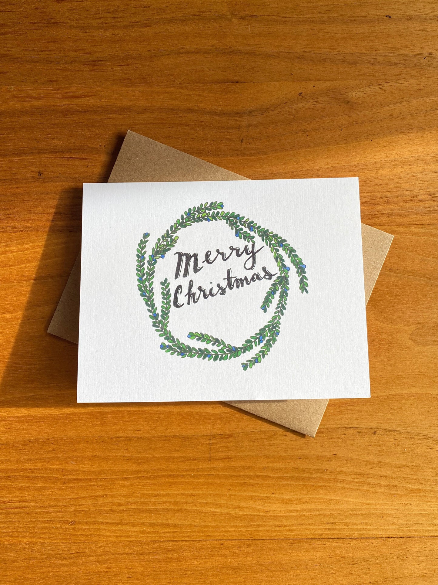 Watercolor holiday wreath card that says "Merry Christmas"