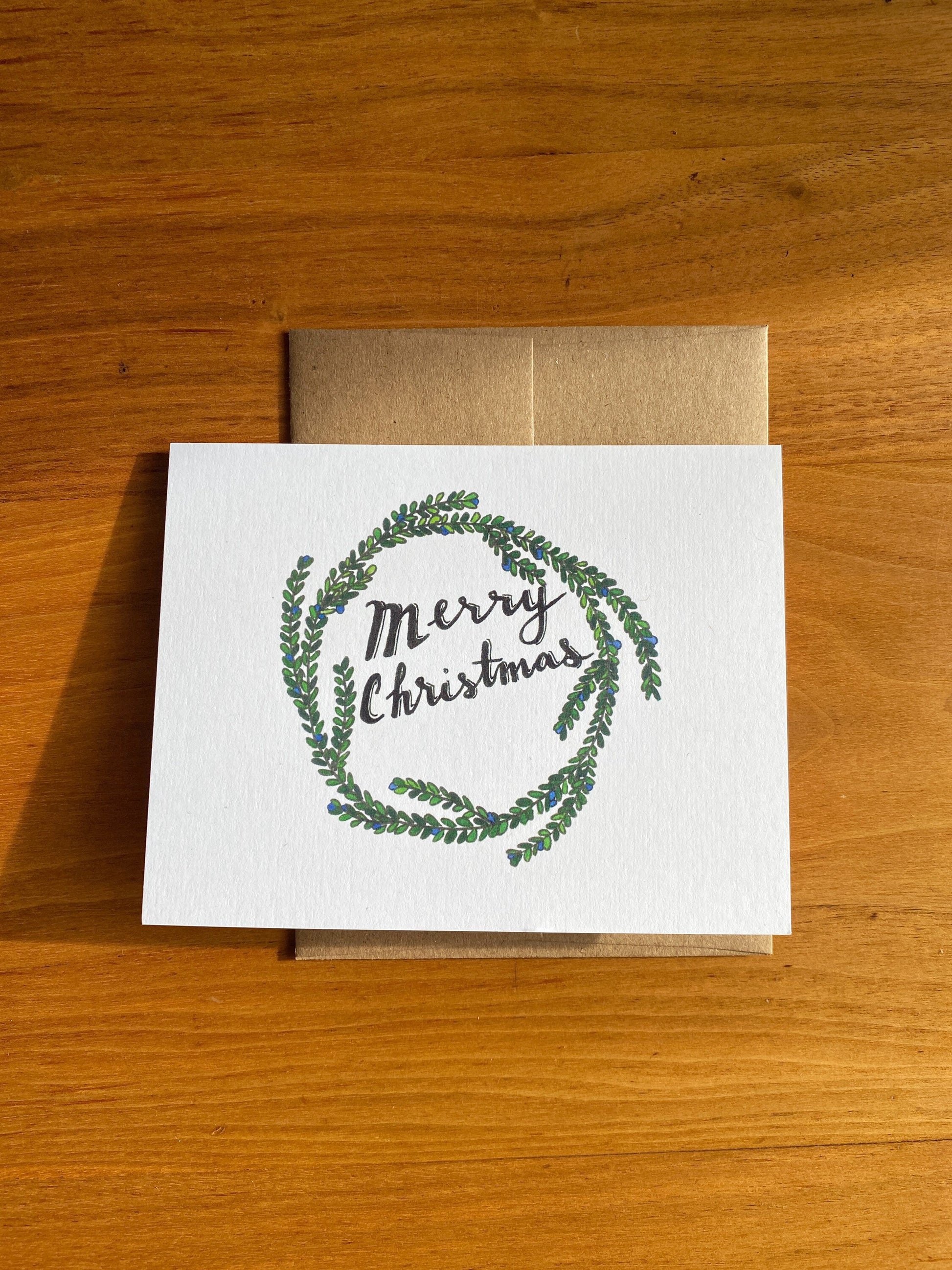 Watercolor holiday wreath card that says "Merry Christmas"