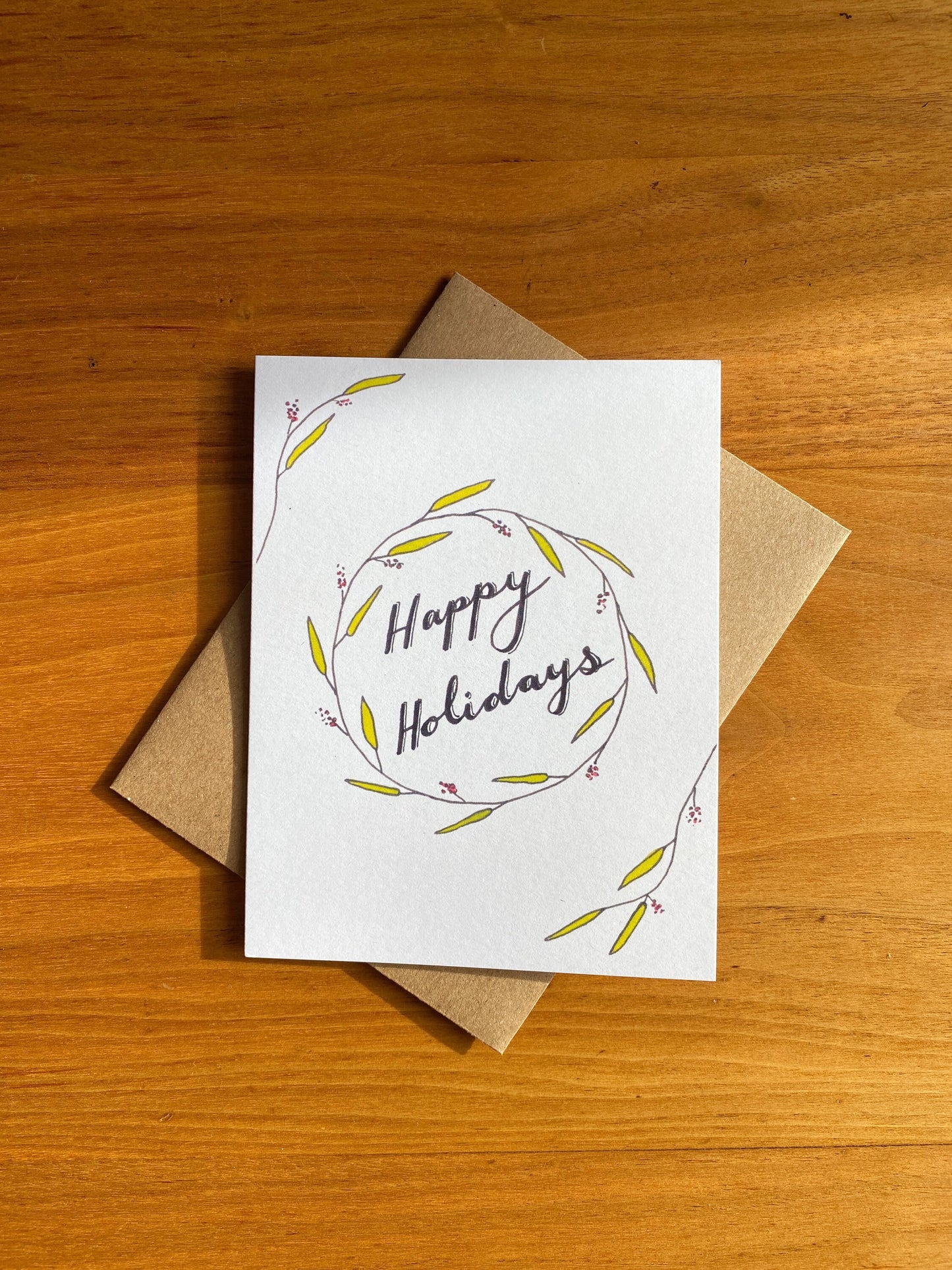 Watercolor greeting card that says "Happy Holidays" with greenery