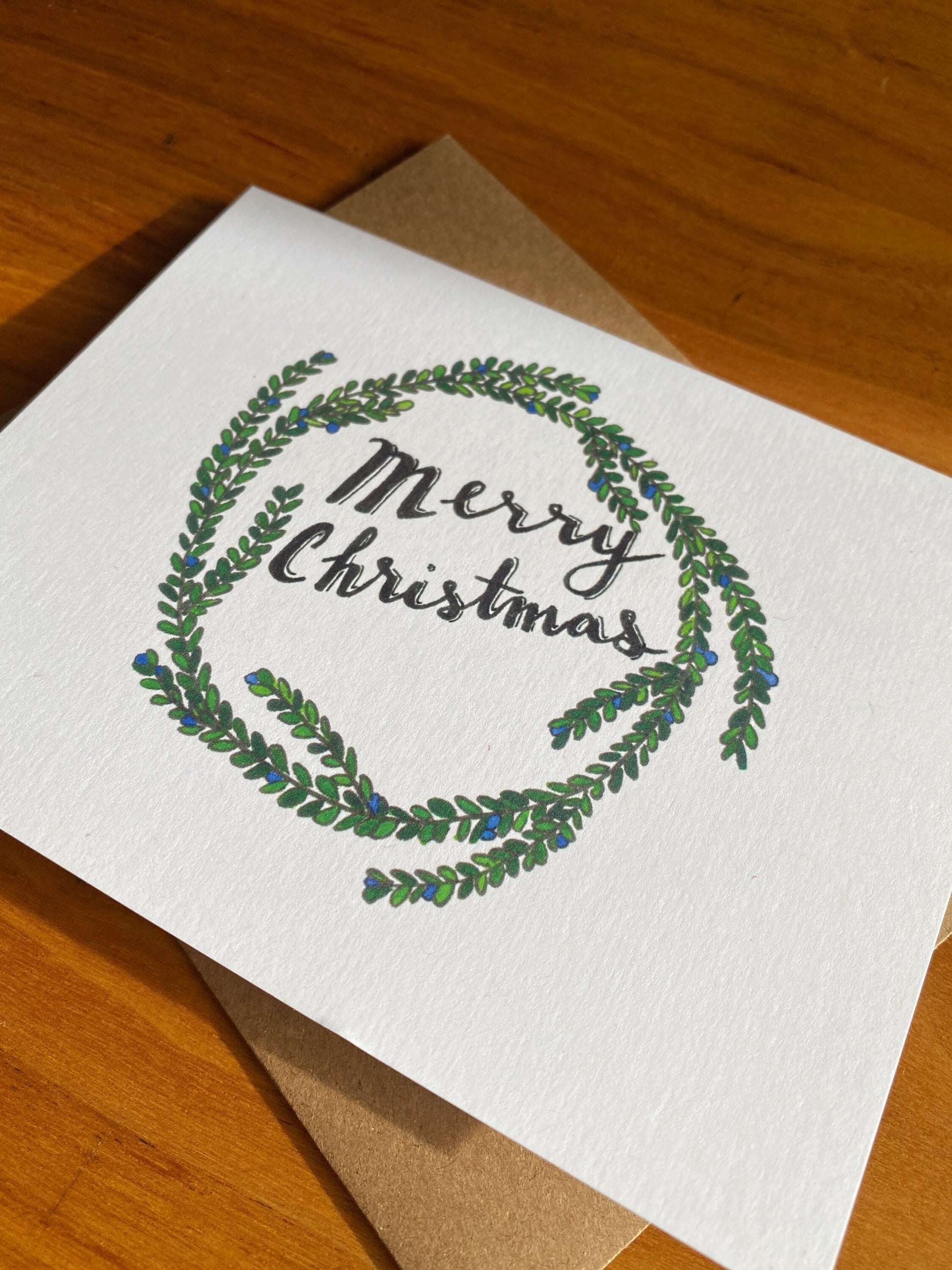 Watercolor holiday wreath card that says "Merry Christmas"