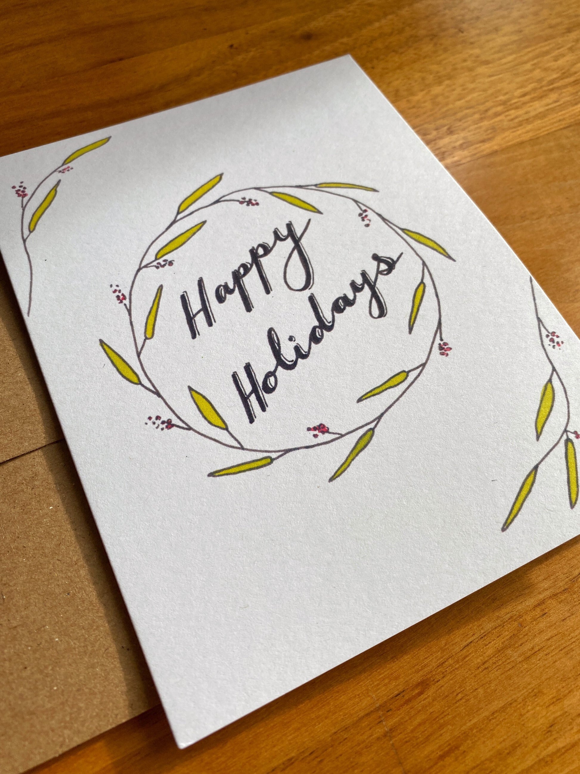 Watercolor greeting card that says "Happy Holidays" with greenery