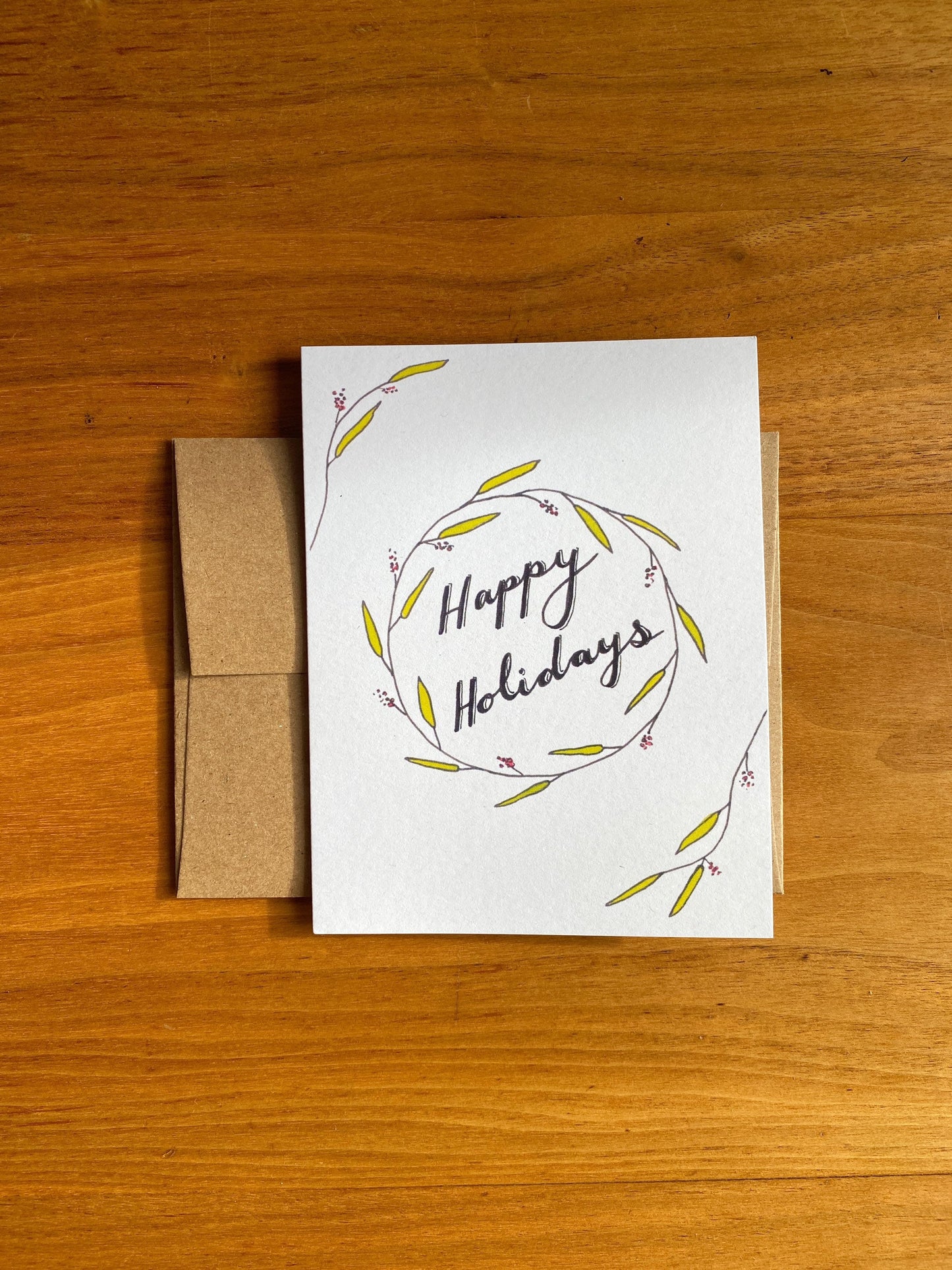 Watercolor greeting card that says "Happy Holidays" with greenery