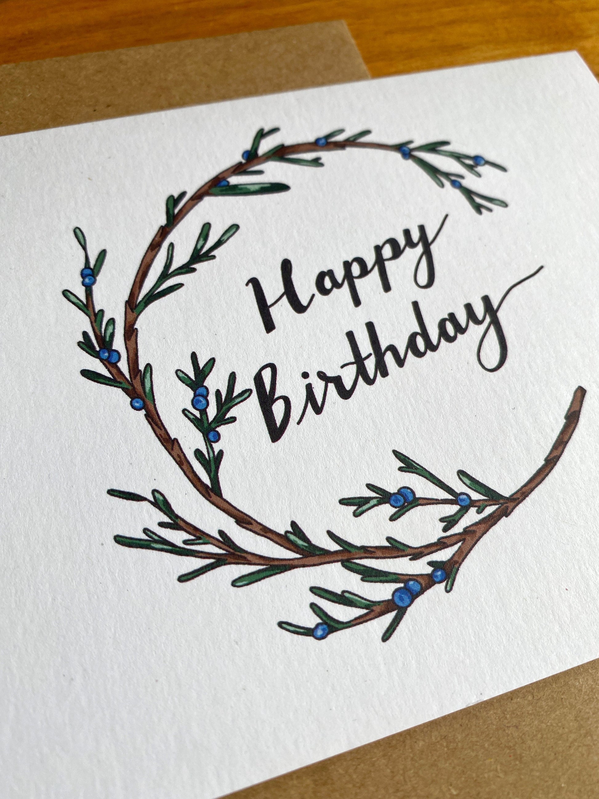 Greeting card with a juniper wreath that says Happy Birthday.