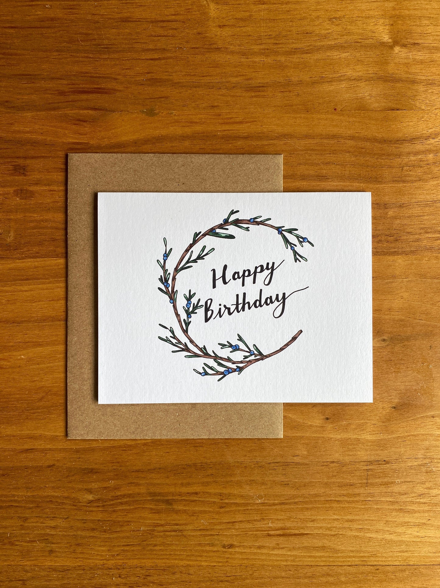 Greeting card with a juniper wreath that says Happy Birthday.