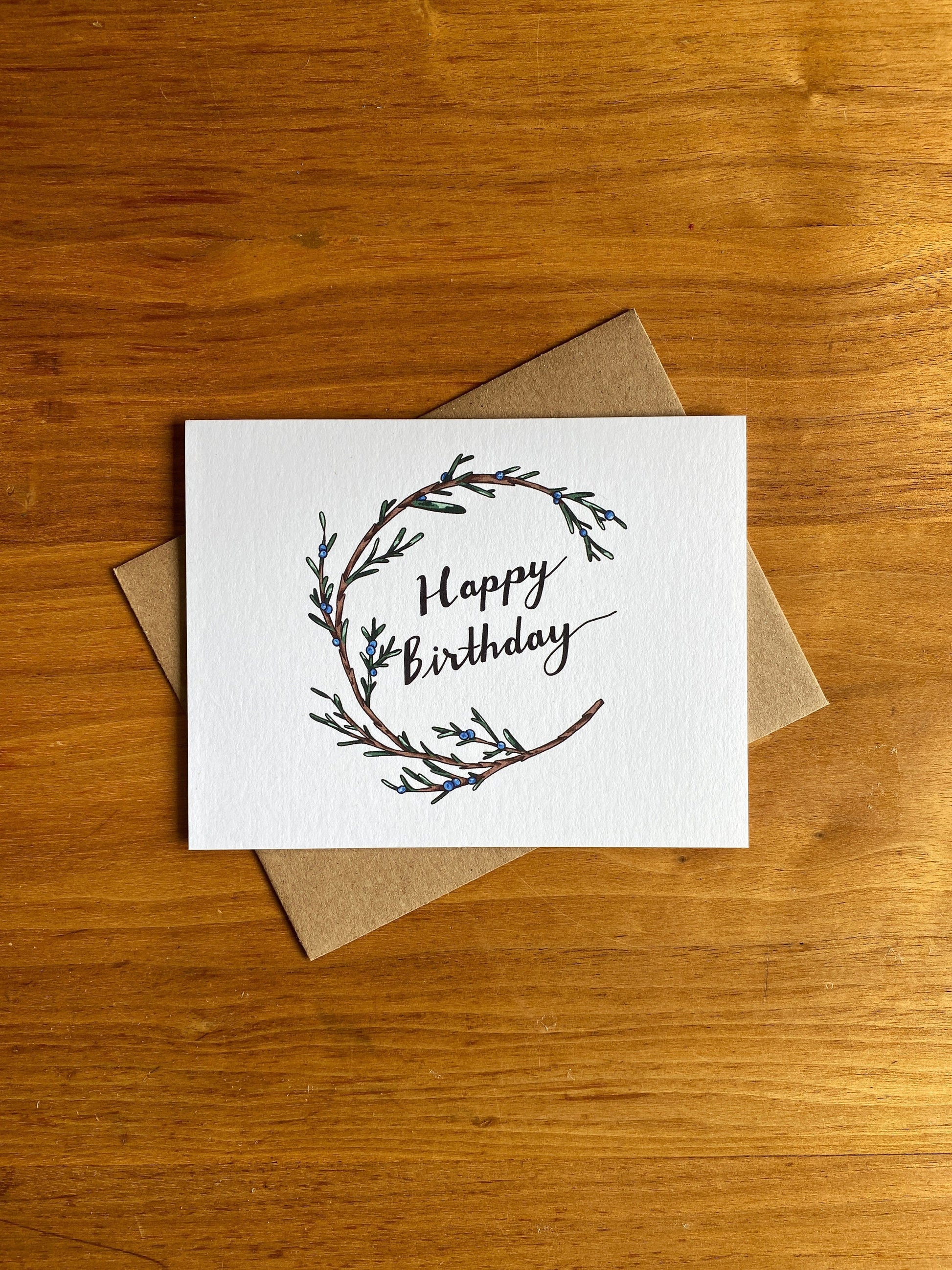 Greeting card with a juniper wreath that says Happy Birthday.